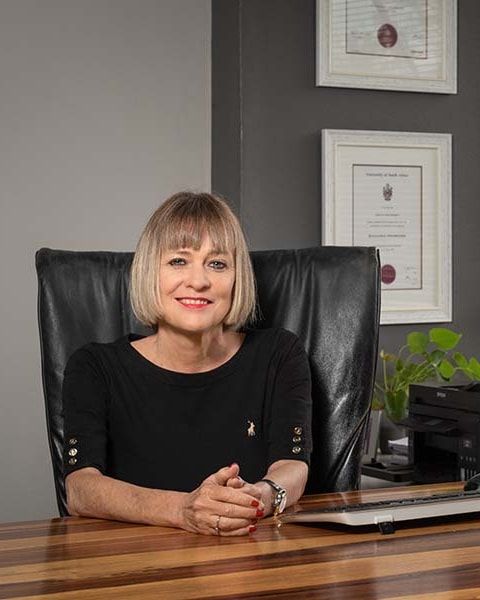 Jo-Anne Cogan, Founder and Director, seated at a desk in the office